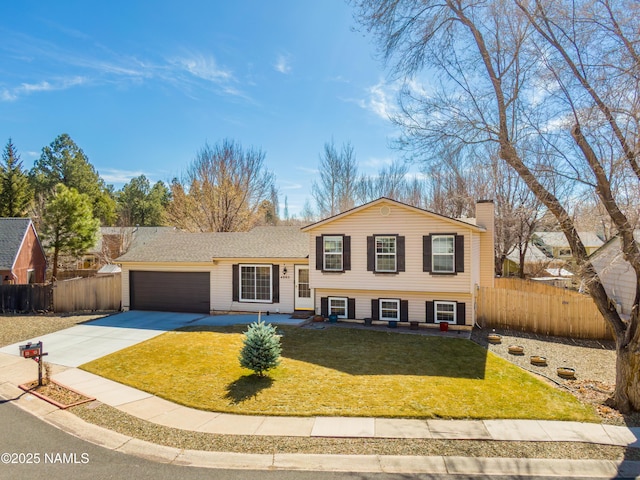 split level home with a garage, driveway, a front yard, and fence