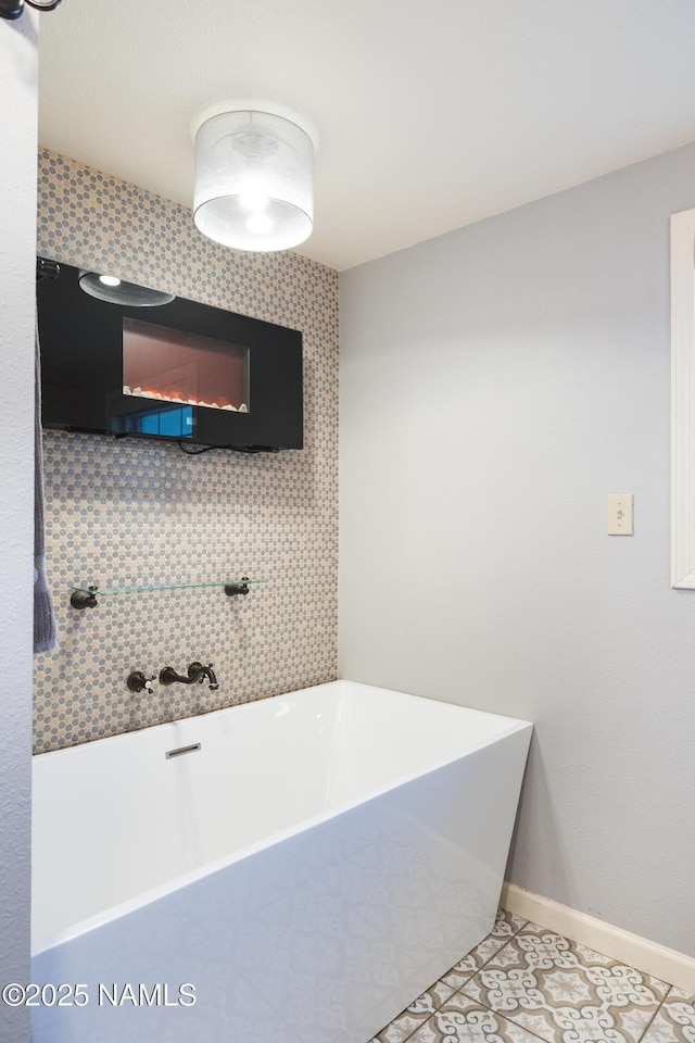 bathroom with a freestanding bath, tile patterned floors, and baseboards