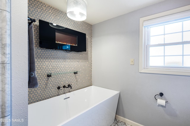 bathroom featuring a freestanding tub and baseboards