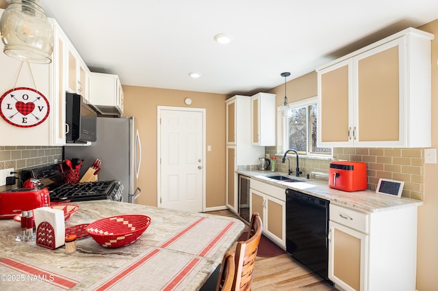 kitchen with a sink, black dishwasher, light countertops, hanging light fixtures, and glass insert cabinets