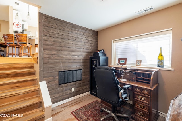 home office featuring wood walls, baseboards, visible vents, and wood finished floors