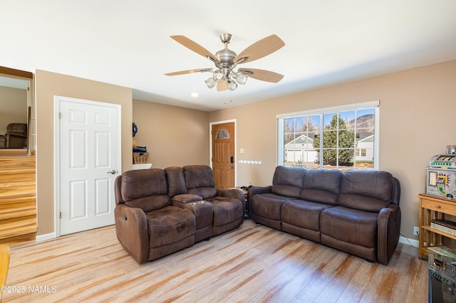 living room with ceiling fan, baseboards, and light wood-style floors