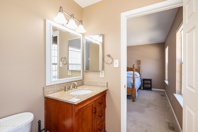 ensuite bathroom featuring baseboards, visible vents, connected bathroom, toilet, and vanity