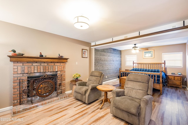 bedroom with a brick fireplace, wood finished floors, and baseboards