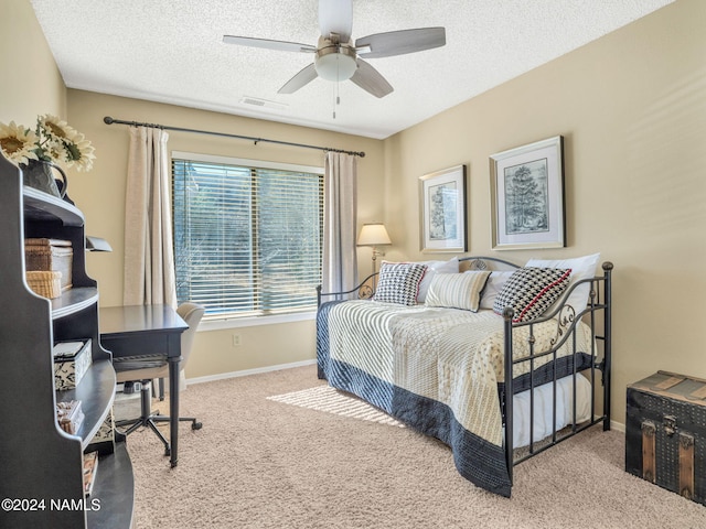 carpeted bedroom with ceiling fan and a textured ceiling