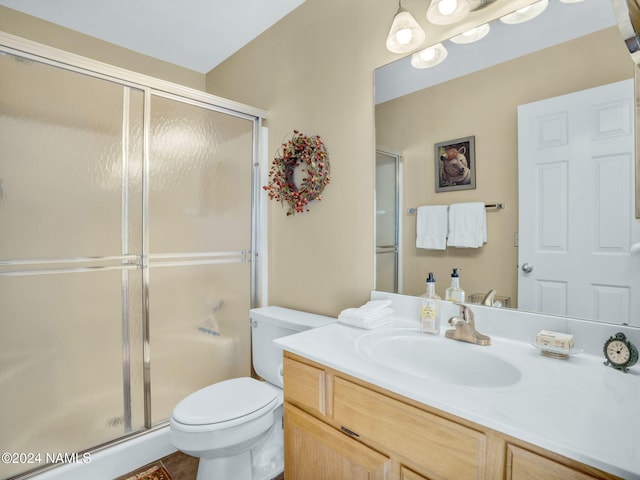 bathroom with vanity, toilet, and a shower with door