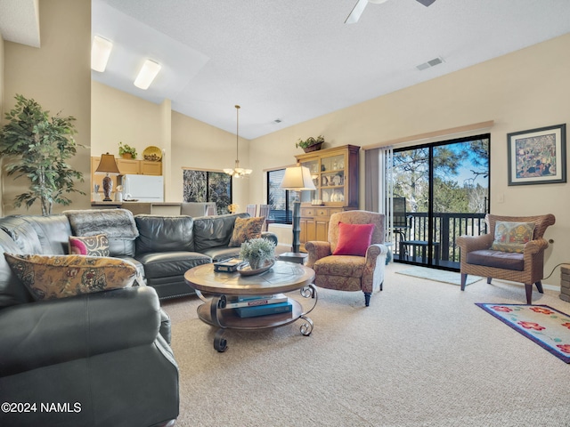 carpeted living room featuring ceiling fan with notable chandelier and vaulted ceiling