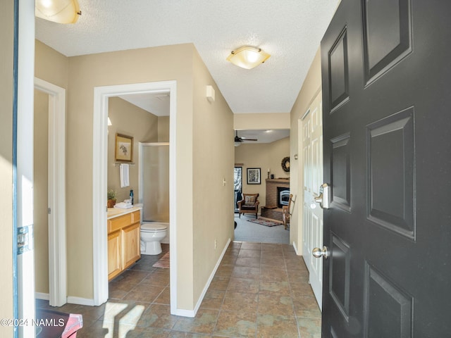 foyer with ceiling fan, a fireplace, and a textured ceiling