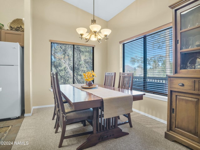 dining room with light carpet, a chandelier, and vaulted ceiling