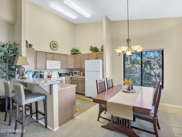 kitchen featuring decorative light fixtures, white appliances, kitchen peninsula, and high vaulted ceiling