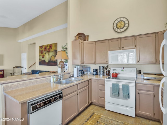 kitchen with sink, white appliances, light brown cabinets, and kitchen peninsula