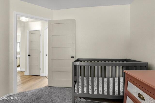 9654 Heritage Dr, Flagstaff, AZ 86004 - carpeted bedroom featuring a nursery area, baseboards, and wood finished floors