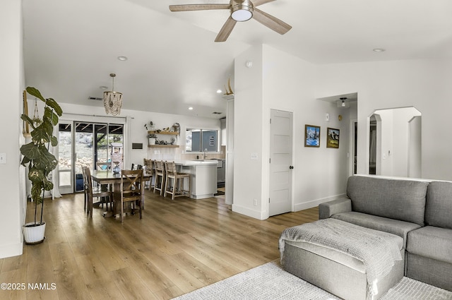 9654 Heritage Dr, Flagstaff, AZ 86004 - living room featuring a ceiling fan, light wood-style flooring, arched walkways, high vaulted ceiling, and baseboards
