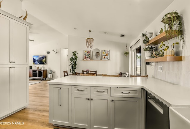 9654 Heritage Dr, Flagstaff, AZ 86004 - kitchen with a peninsula, vaulted ceiling, stainless steel dishwasher, light wood-type flooring, and light countertops