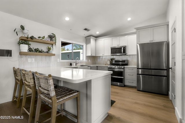 9654 Heritage Dr, Flagstaff, AZ 86004 - kitchen with stainless steel appliances, a peninsula, a sink, a kitchen bar, and light countertops