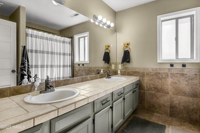 9654 Heritage Dr, Flagstaff, AZ 86004 - bathroom featuring double vanity, tile patterned flooring, curtained shower, wainscoting, and tile walls