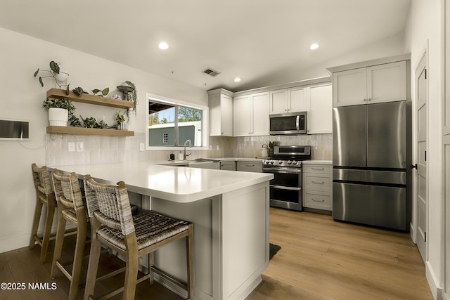 9654 Heritage Dr, Flagstaff, AZ 86004 - kitchen featuring appliances with stainless steel finishes, a peninsula, a sink, a kitchen bar, and light countertops