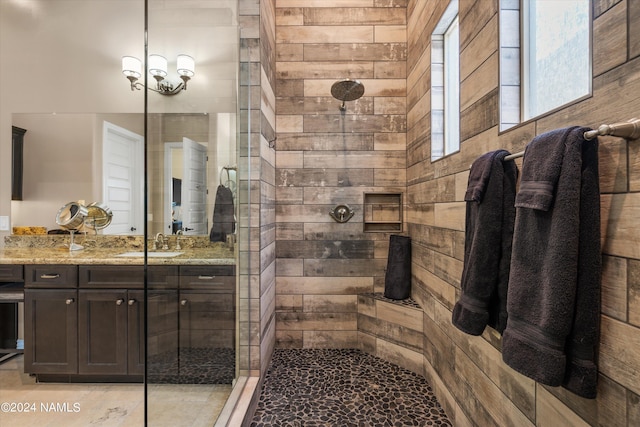 bathroom with a tile shower, wood walls, and vanity