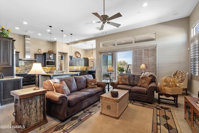 living room with ceiling fan with notable chandelier and light hardwood / wood-style flooring