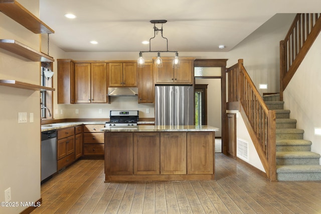 3135 Ancient Trl, Flagstaff, AZ 86005 - kitchen with appliances with stainless steel finishes, under cabinet range hood, open shelves, a kitchen island, and hardwood / wood-style flooring