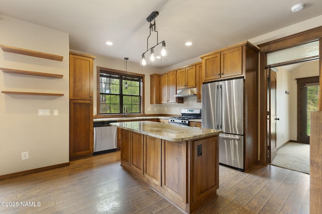 3135 Ancient Trl, Flagstaff, AZ 86005 - kitchen with appliances with stainless steel finishes, under cabinet range hood, a kitchen island, dark wood finished floors, and brown cabinetry