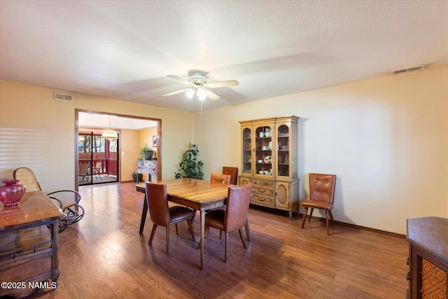 dining space featuring hardwood / wood-style flooring, a textured ceiling, and ceiling fan