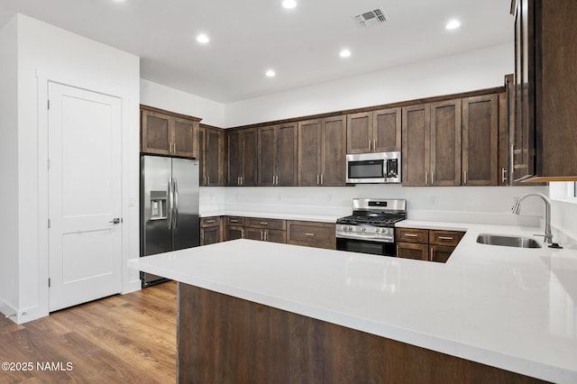 555 N Valerian Ln Lot 24, Flagstaff, AZ 86004 - kitchen featuring stainless steel appliances, a sink, dark brown cabinetry, light countertops, and light wood-type flooring