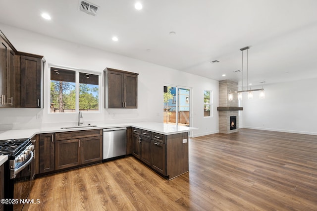 555 N Valerian Ln Lot 24, Flagstaff, AZ 86004 - kitchen with appliances with stainless steel finishes, a sink, dark brown cabinets, a peninsula, and wood finished floors
