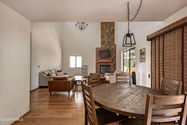 dining area featuring wood-type flooring, a wealth of natural light, and a stone fireplace