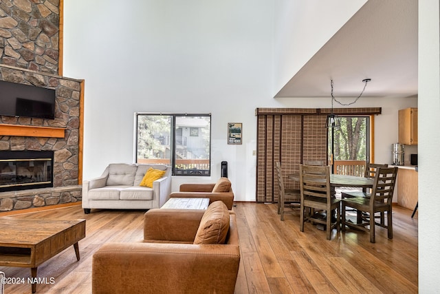 living room with light hardwood / wood-style floors, a towering ceiling, and a fireplace