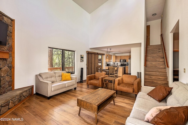 living room with high vaulted ceiling, light hardwood / wood-style floors, and a stone fireplace