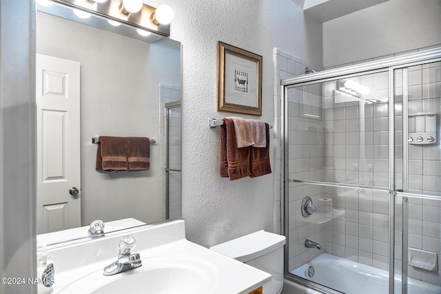 full bathroom with combined bath / shower with glass door, vanity, and toilet