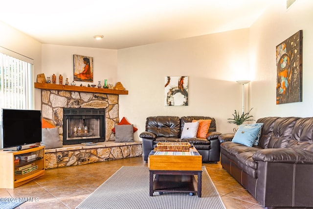 tiled living room with a stone fireplace