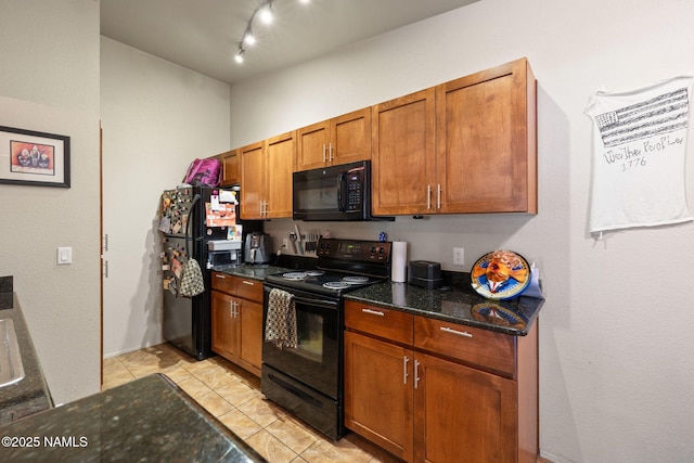 kitchen with brown cabinets, rail lighting, dark stone countertops, light tile patterned floors, and black appliances