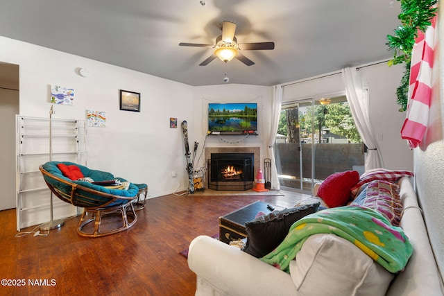 living area featuring a fireplace with flush hearth, a ceiling fan, and wood finished floors