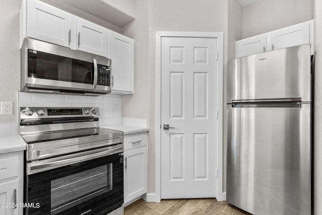 kitchen featuring light wood finished floors, light countertops, backsplash, appliances with stainless steel finishes, and white cabinetry