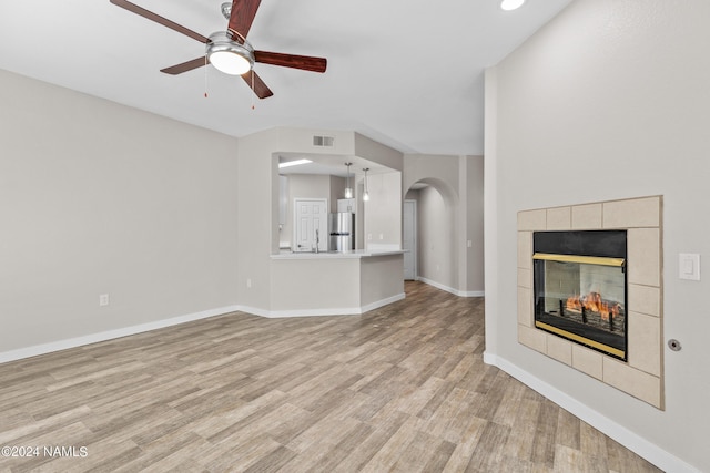 unfurnished living room with a ceiling fan, visible vents, baseboards, light wood-type flooring, and a tiled fireplace