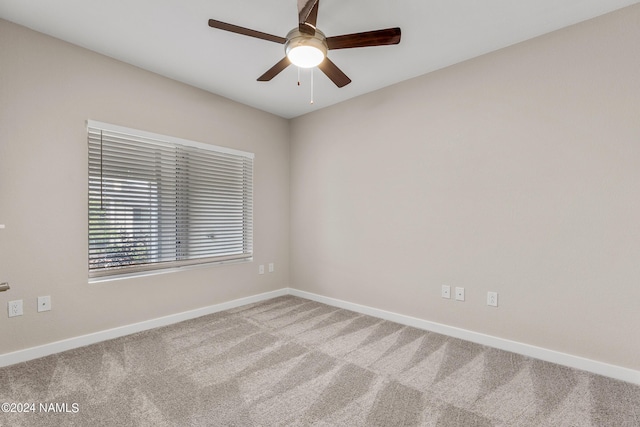 carpeted empty room featuring ceiling fan and baseboards