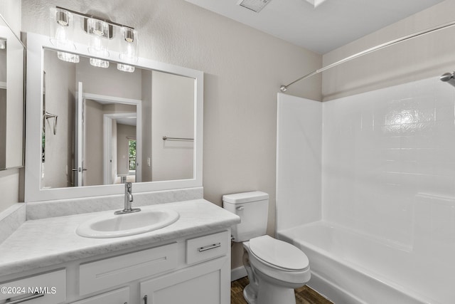 bathroom with visible vents, toilet, vanity, wood finished floors, and shower / bathtub combination