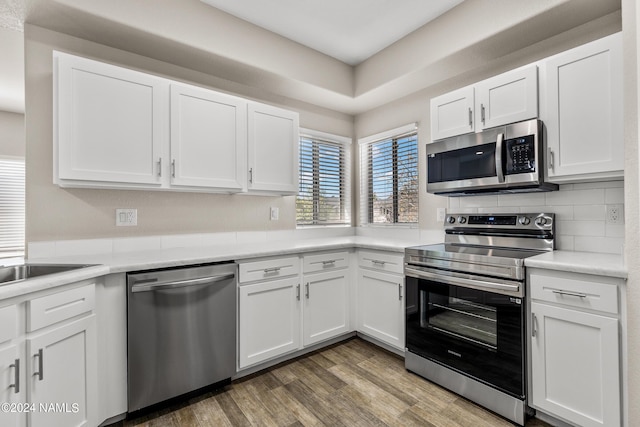 kitchen featuring white cabinetry, appliances with stainless steel finishes, decorative backsplash, and wood finished floors