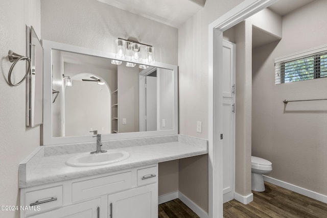 bathroom with toilet, baseboards, wood finished floors, and vanity