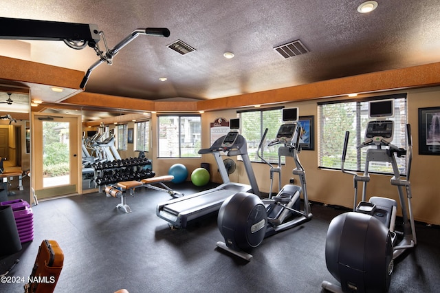 exercise room featuring a healthy amount of sunlight, visible vents, and a textured ceiling