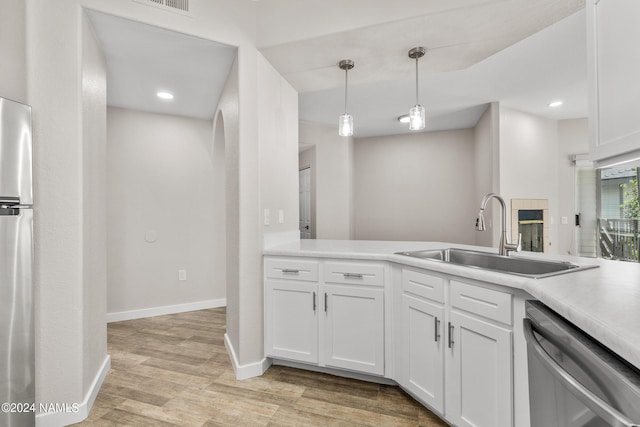 kitchen with stainless steel appliances, a sink, white cabinets, light countertops, and light wood finished floors