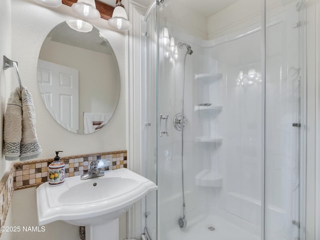 bathroom with a sink, decorative backsplash, and a shower stall