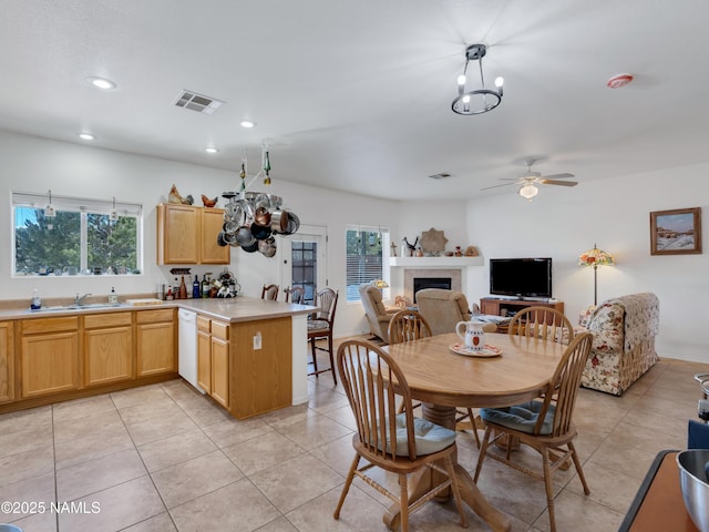 dining room featuring a tiled fireplace, plenty of natural light, visible vents, and light tile patterned floors