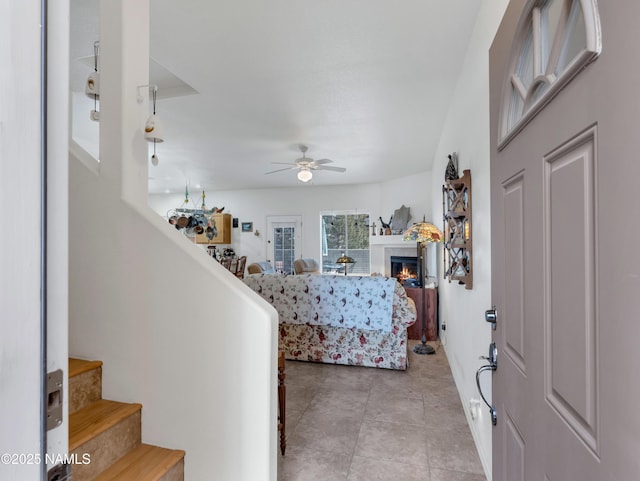 9123 W Arden Ln, Bellemont, AZ 86015 - entryway featuring stairs, a ceiling fan, a glass covered fireplace, and light tile patterned flooring