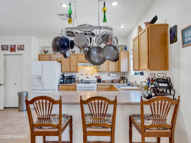 kitchen featuring visible vents, light brown cabinets, white appliances, a peninsula, and light tile patterned floors