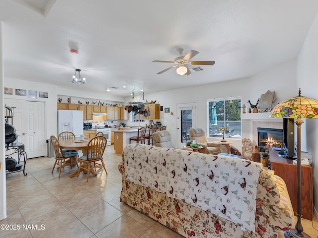 living room with light tile patterned floors, visible vents, ceiling fan, and a fireplace