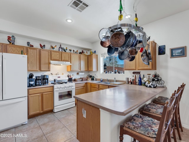 kitchen featuring visible vents, under cabinet range hood, a sink, white appliances, and a peninsula