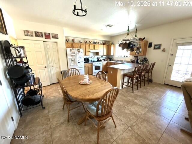 9123 W Arden Ln, Bellemont, AZ 86015 - dining area featuring light tile patterned flooring, a chandelier, visible vents, and a wealth of natural light